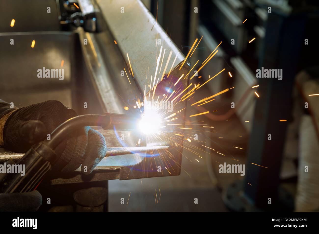 Worker is welding with semi-automatic argon gas shielded welding machine on metal that has sparkles in it Stock Photo