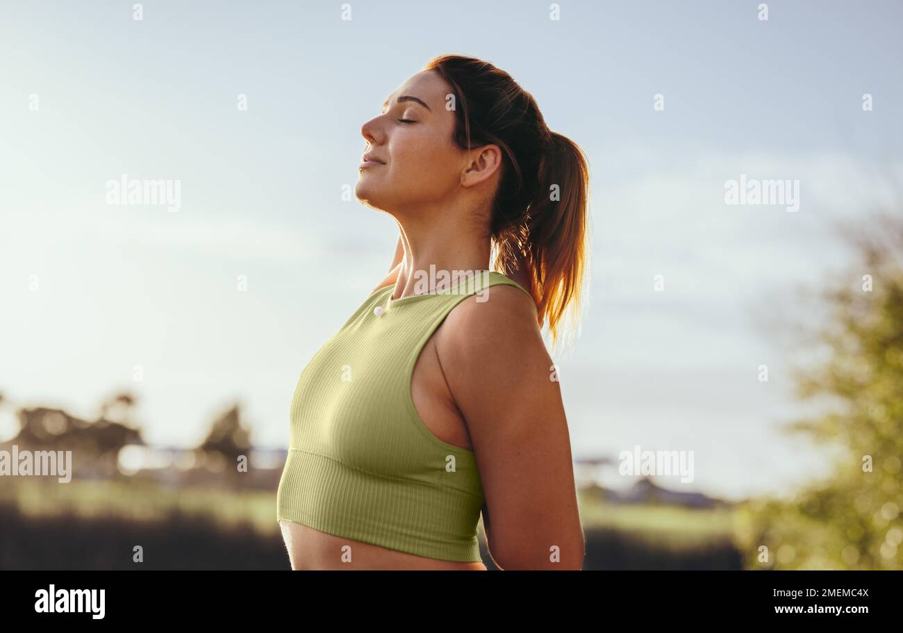 Fit woman practicing the standing cow face pose outdoors. Woman doing a warmup exercise during her morning workout. Sports woman practicing hatha yoga Stock Photo