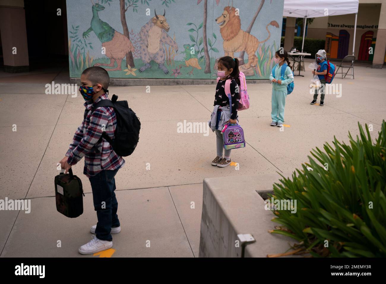 Socially distanced kindergarten students wait for their parents to pick