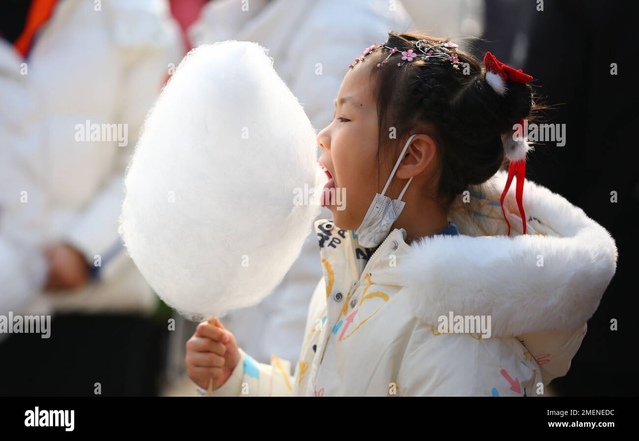 Tengzhou, China's Shandong Province. 22nd Jan, 2023. A girl eats cotton candy in Xigang Township of Tengzhou, east China's Shandong Province, Jan. 22, 2023. People enjoy various kinds of cuisine in China during the Spring Festival holiday. Credit: Li Zhijun/Xinhua/Alamy Live News Stock Photo