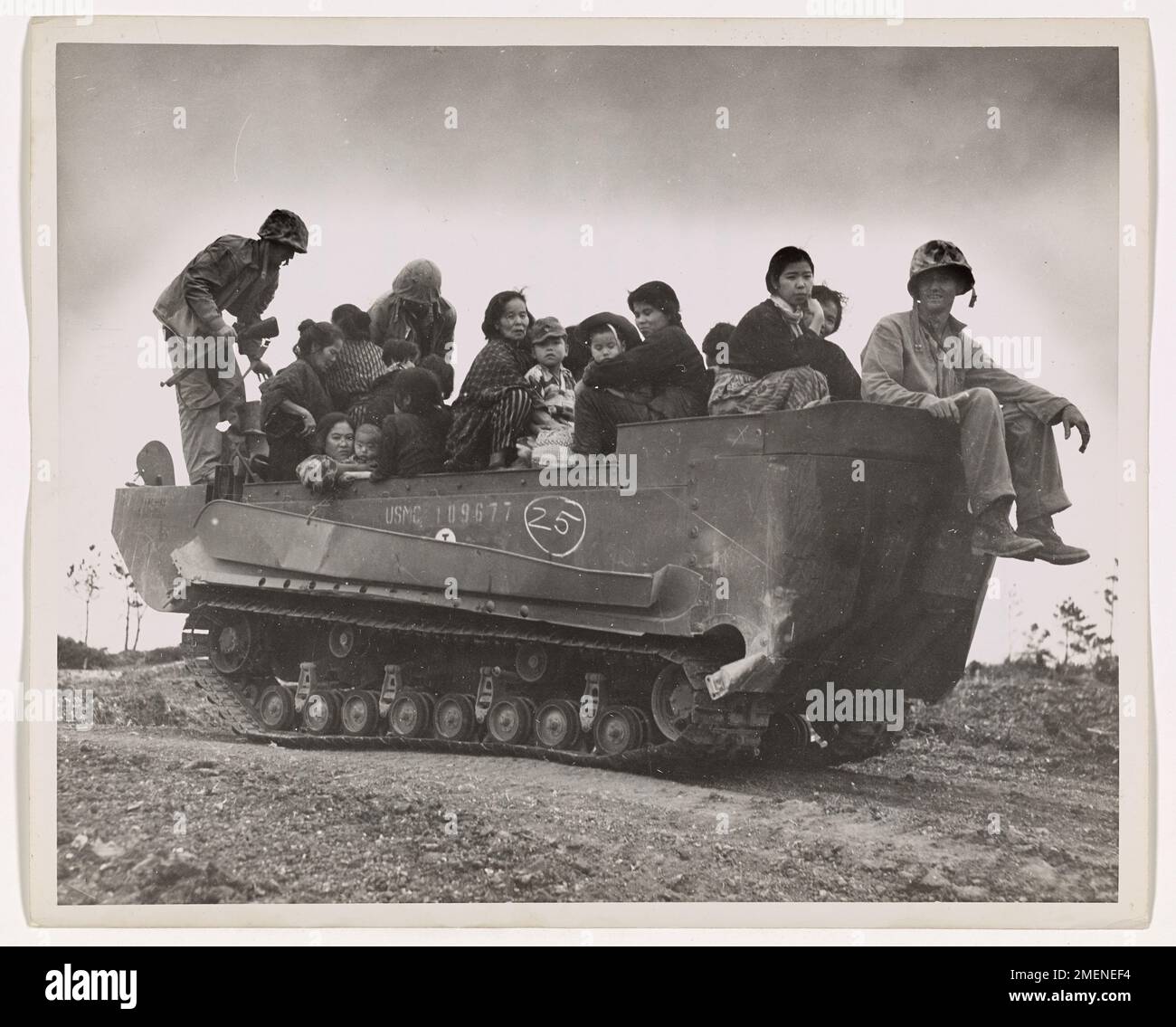 During the Okinawa invasion, a Marine amphibious craft taxis Okinawan civilians to a refugee camp, away from the conflict. The Coast Guard photographer captures the varying facial expressions of the women aboard, including one woman enjoying the unusual American 'taxicab.' Stock Photo