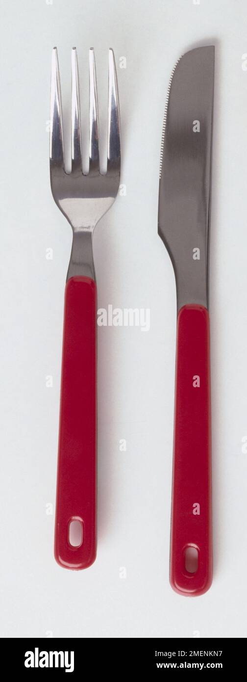 A knife and fork, both with red plastic handles. Stock Photo