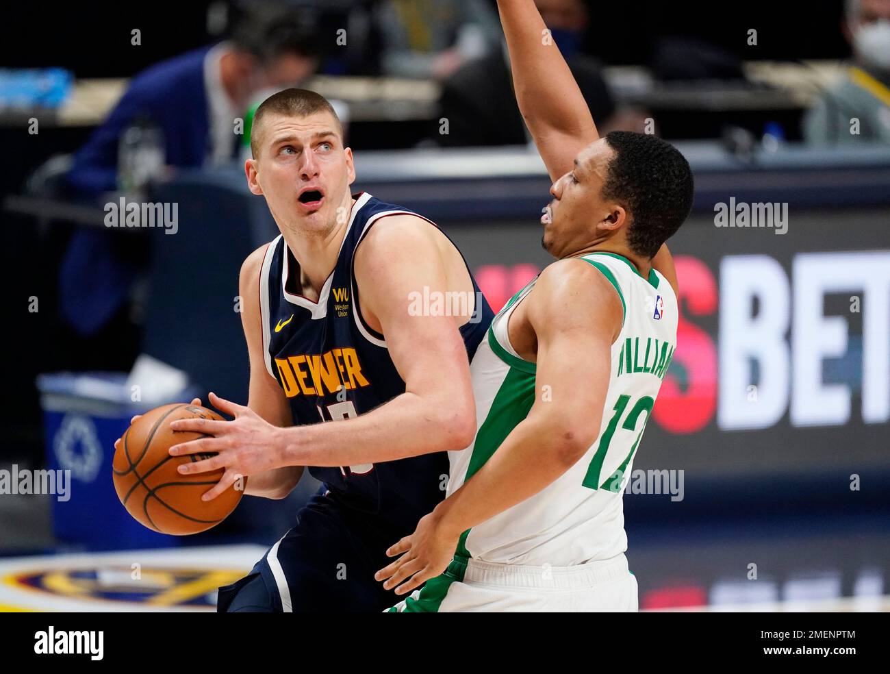 Denver Nuggets center Nikola Jokic, left, turns to shoot as Boston 