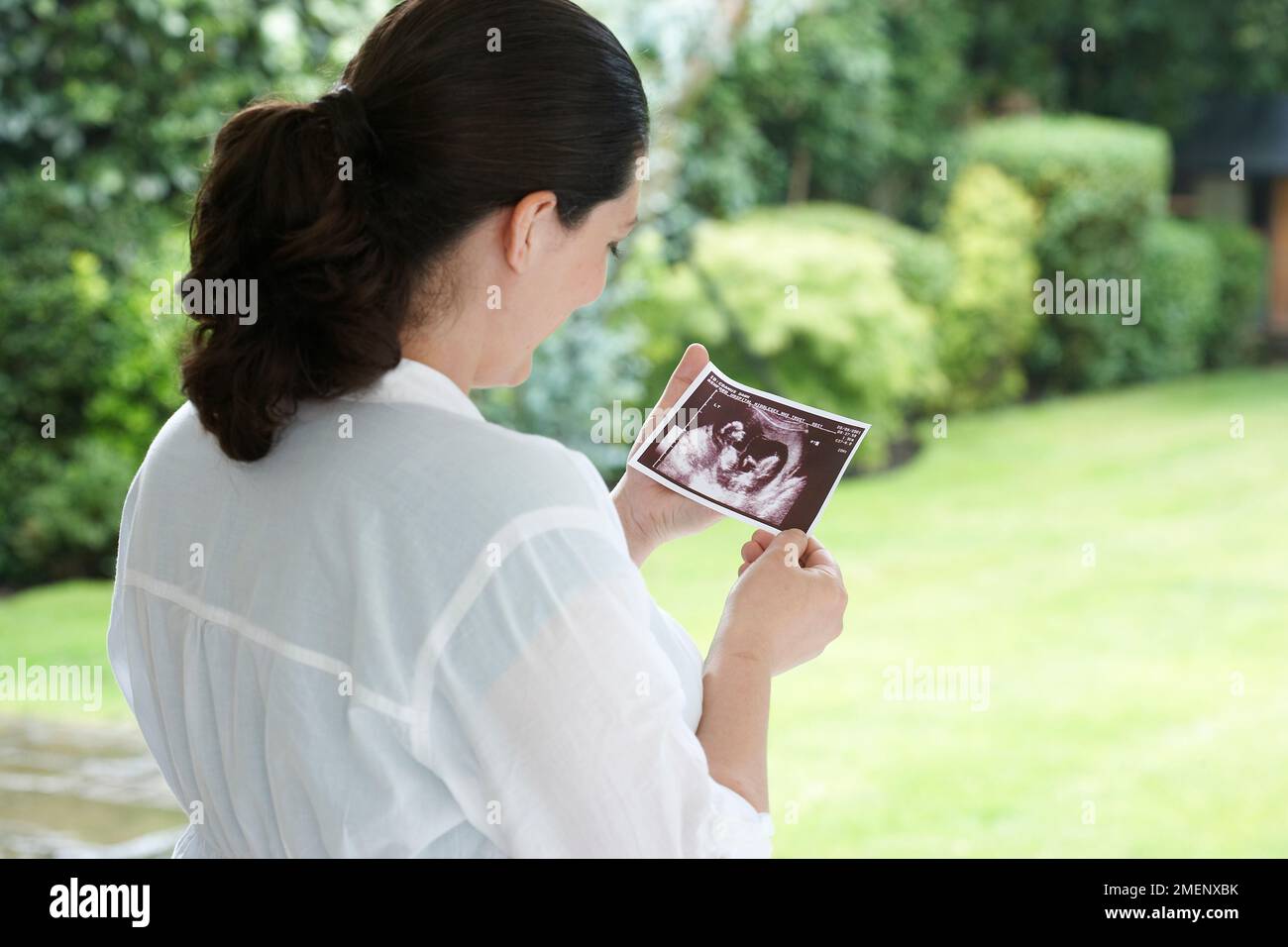Pregnant woman holding sonogram of twin babies Stock Photo - Alamy