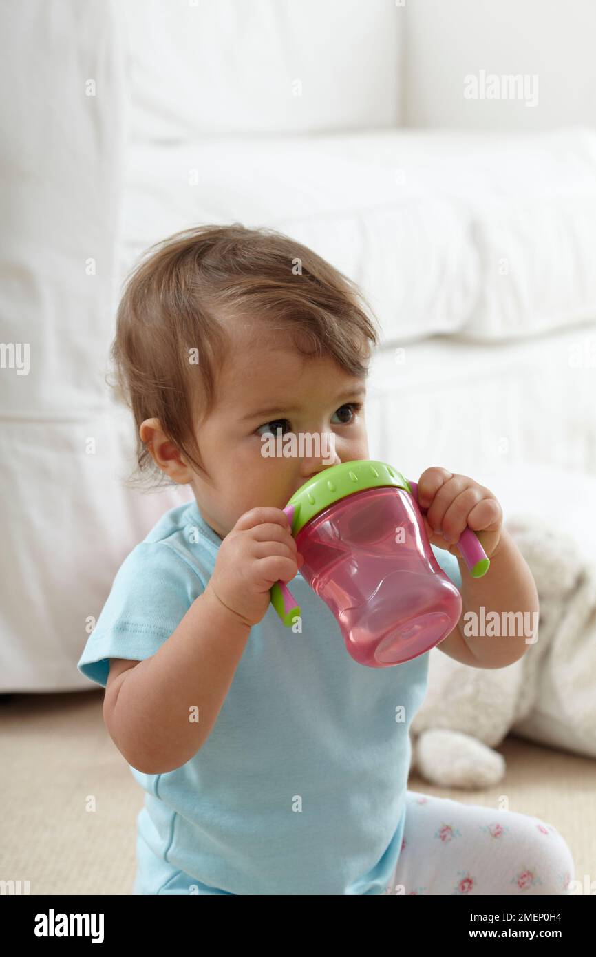 https://c8.alamy.com/comp/2MEP0H4/baby-girl-sitting-on-carpet-drinking-from-sippy-cup-side-view-115-months-2MEP0H4.jpg