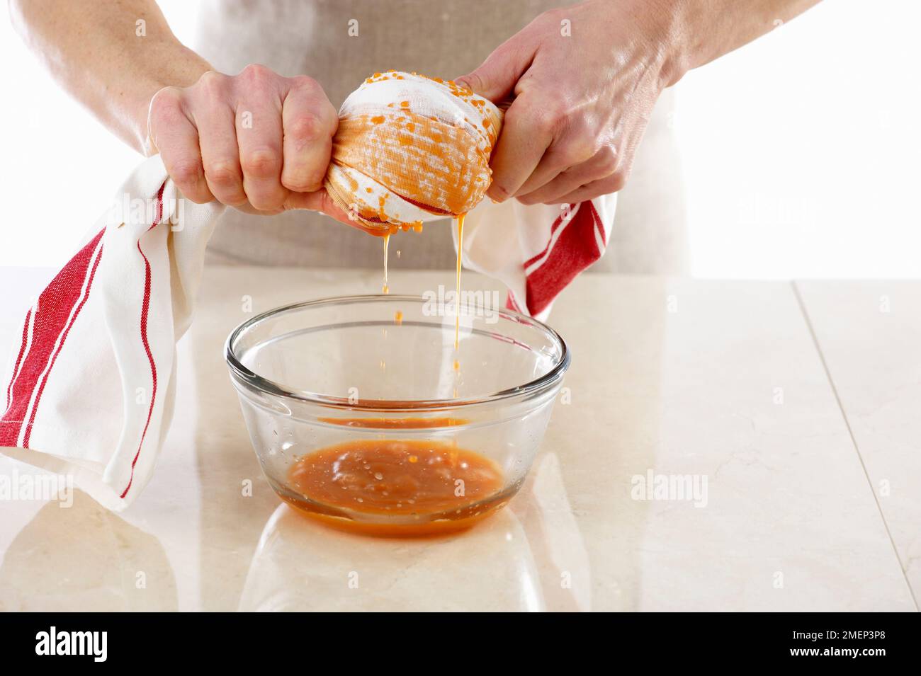 Making Carrot Cake, squeezing grated carrot in tea towel to remove excess liquid Stock Photo