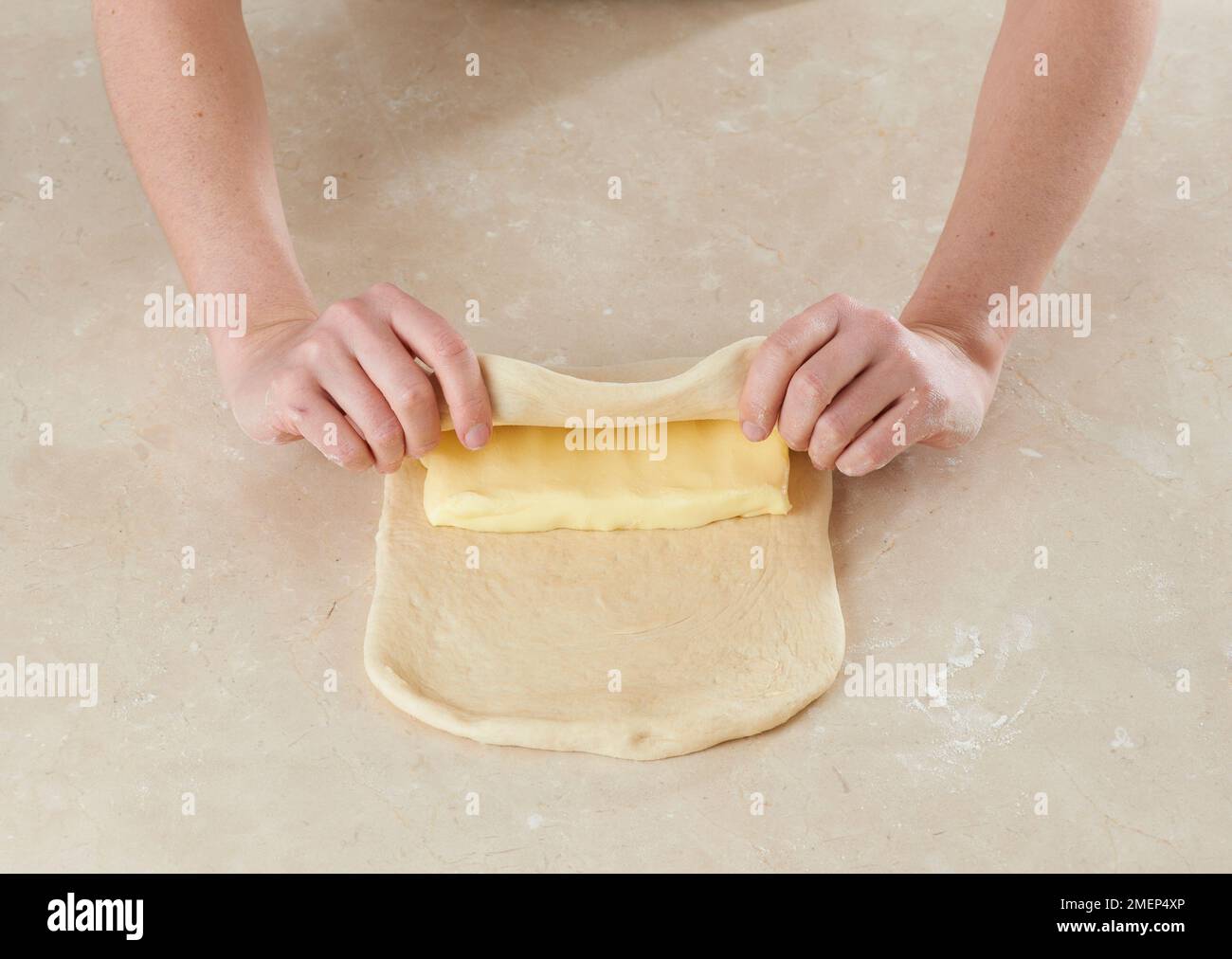Making croissants, placing chilled butter in centre of dough and
