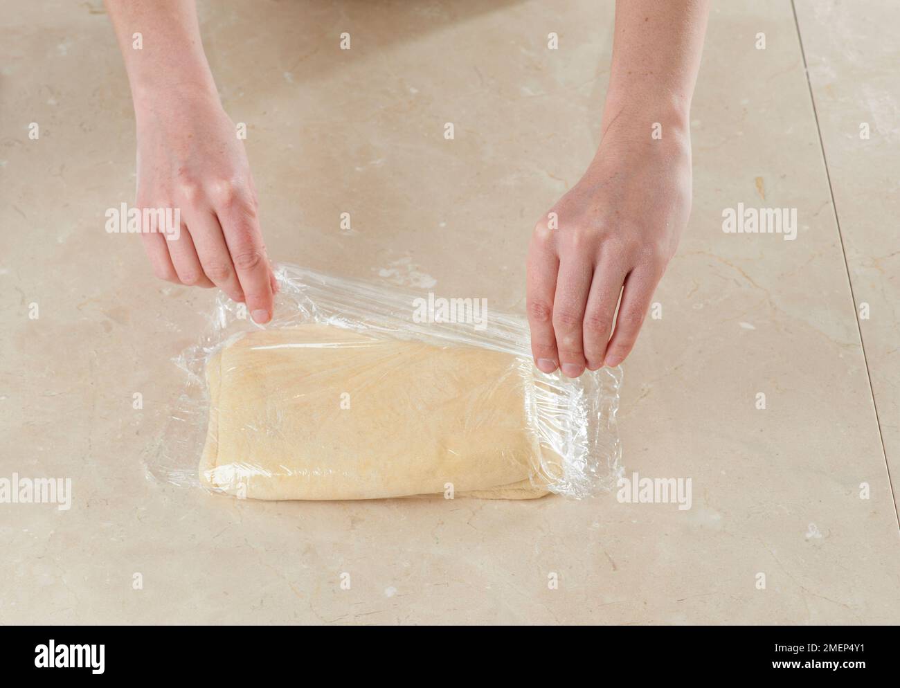 Making Danish Pastries, wrapping dough in cling film and chilling Stock