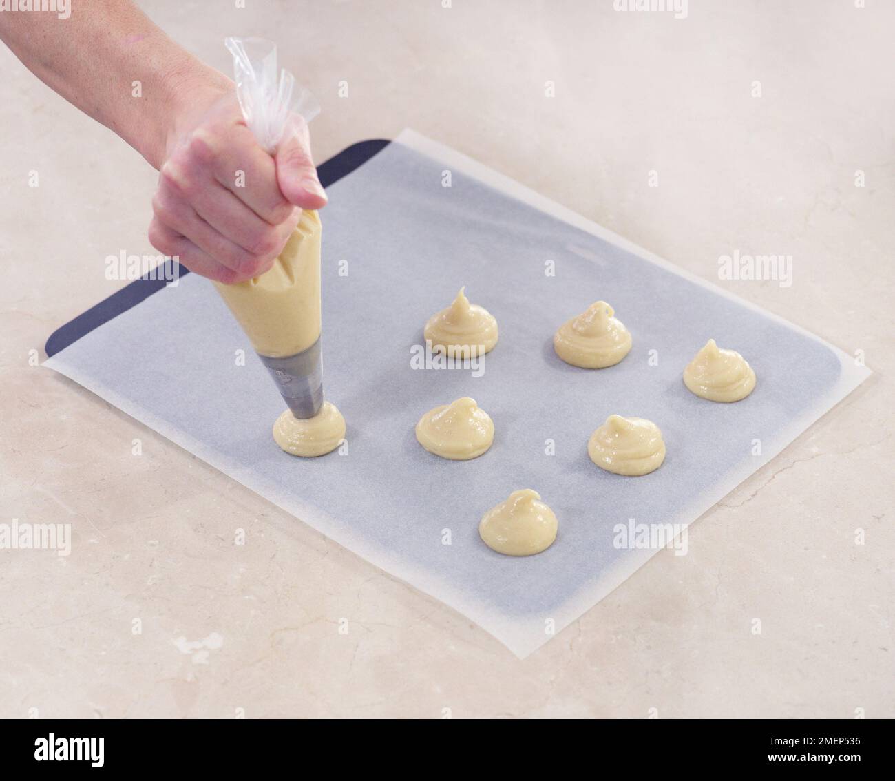 Making Profiteroles, piping mixture on baking sheet covered with