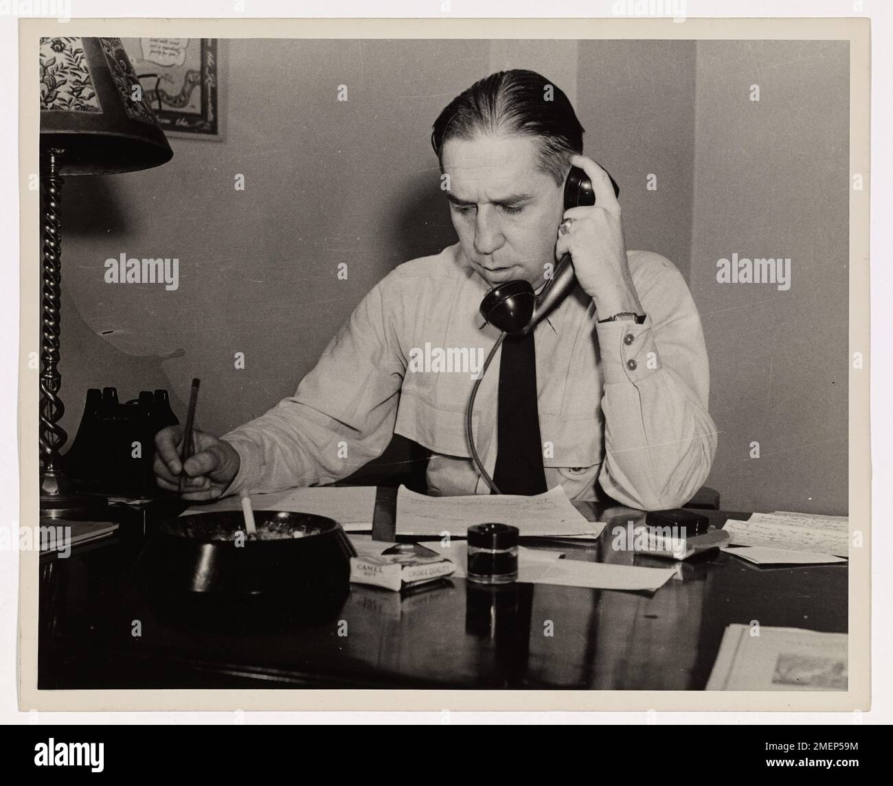 Frank T. Kenner is pictured at his desk, speaking on the phone. He is engaged in a professional conversation while performing his duties. Stock Photo