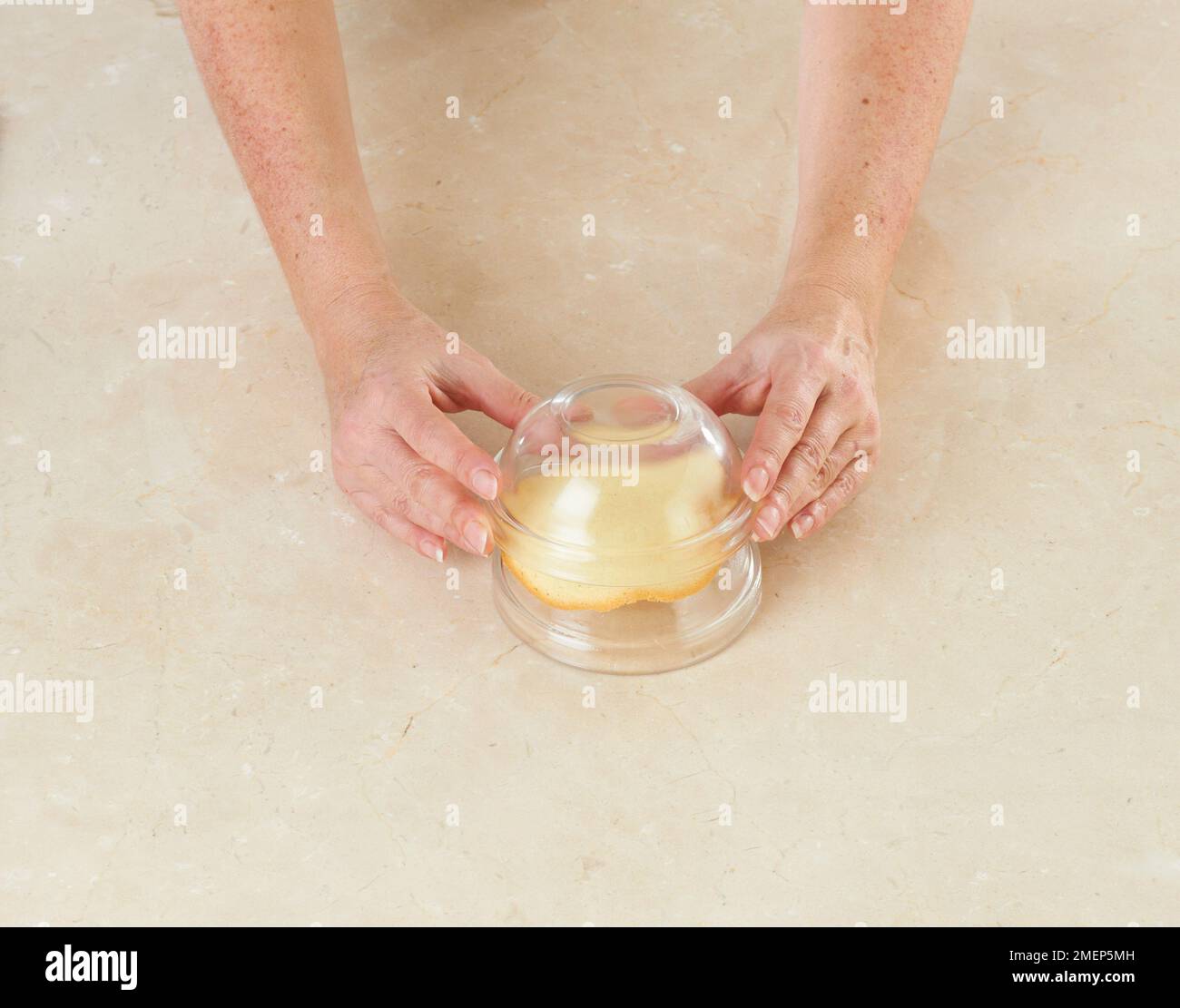 Placing glass bowl on Tuile on top of small glass bowl Stock Photo