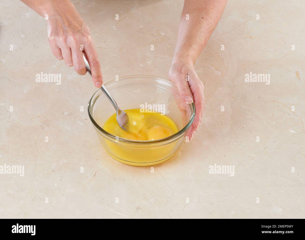 Using fork to whisk eggs in glass mixing bowl Stock Photo Alamy