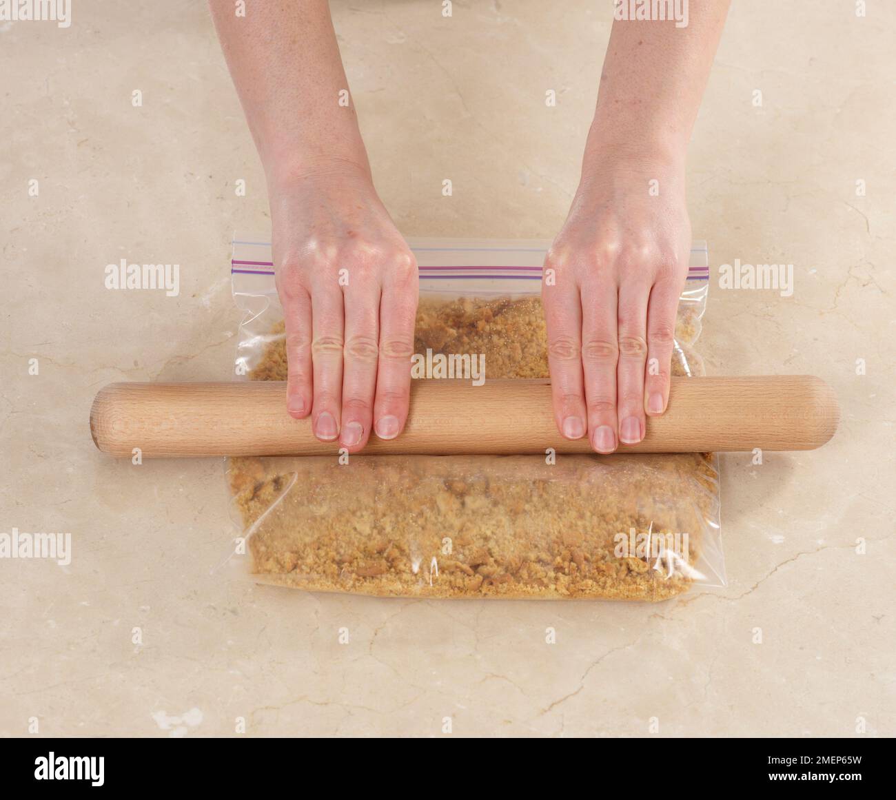 Crushing digestive biscuits to crumbs with a rolling pin, for