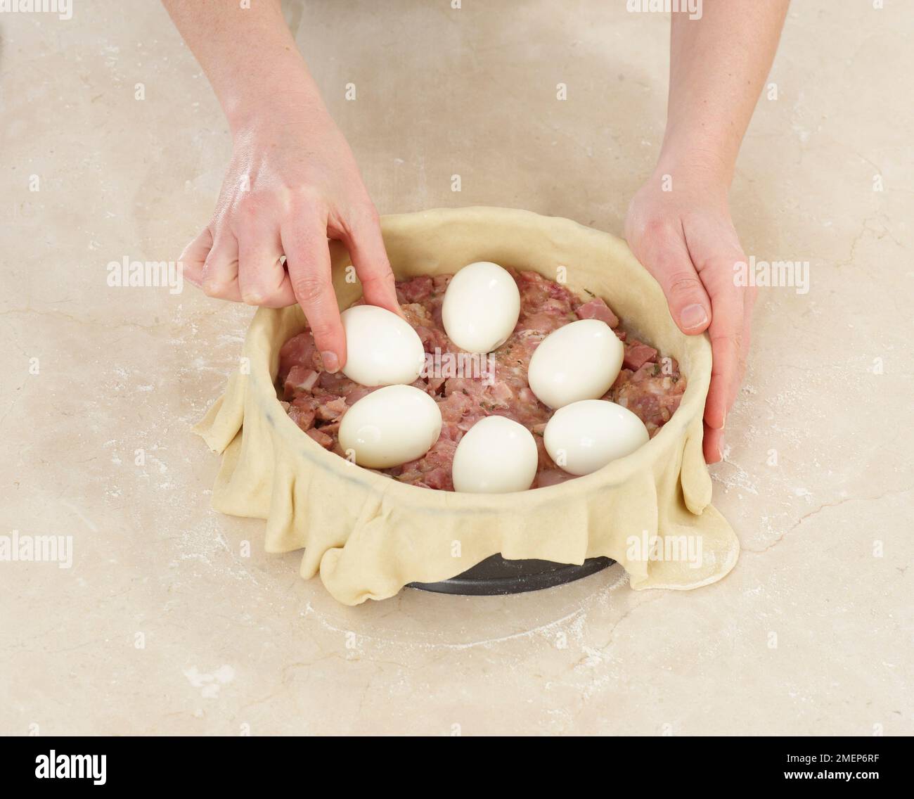 Chicken and Ham Raised Pie, placing boiled eggs on meat mixture Stock