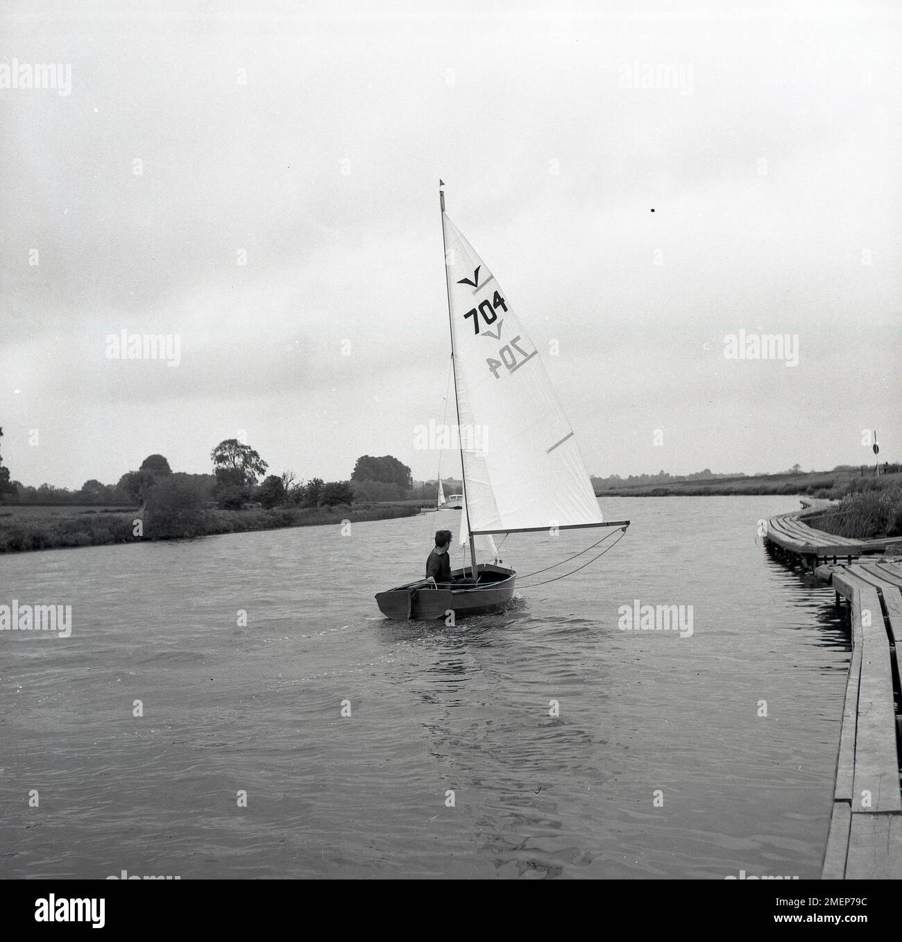 1960s, historical, a boy sailing a dinghy boat along the Norfolk Broads