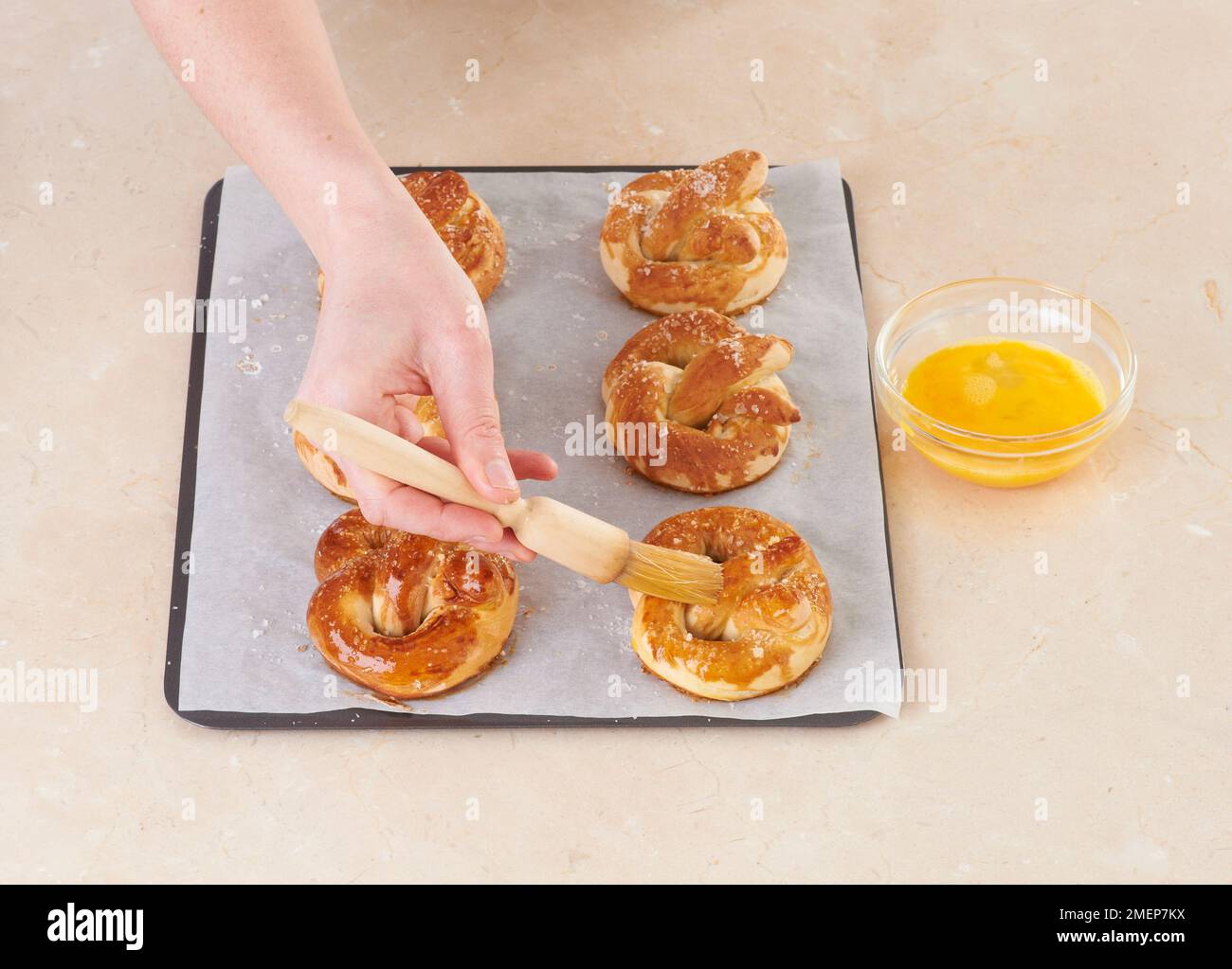 Covering pretzels with egg yoke using basting brush Stock Photo