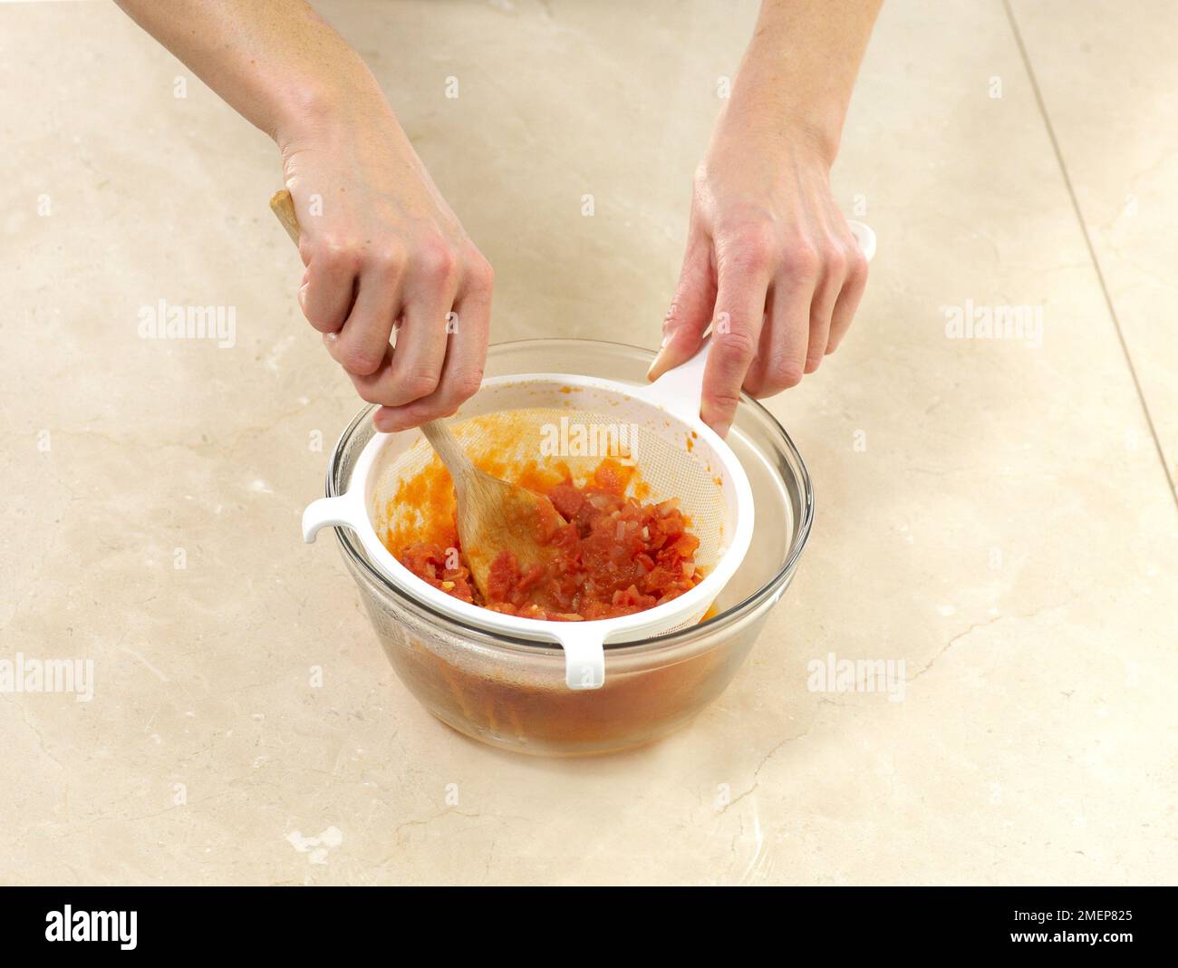 Passing tomato sauce through sieve Stock Photo Alamy