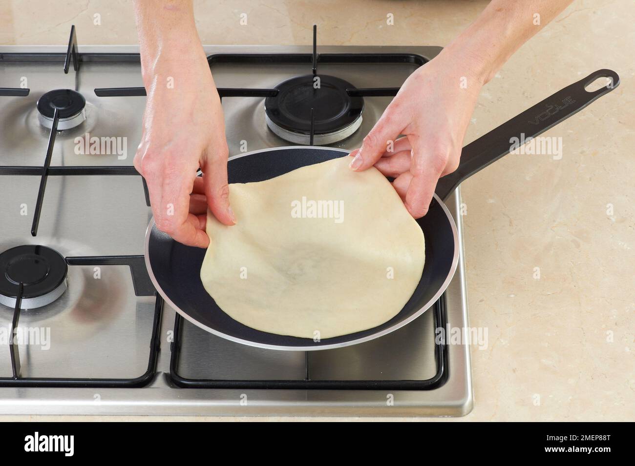 Placing tortilla in frying pan on gas hob Stock Photo Alamy