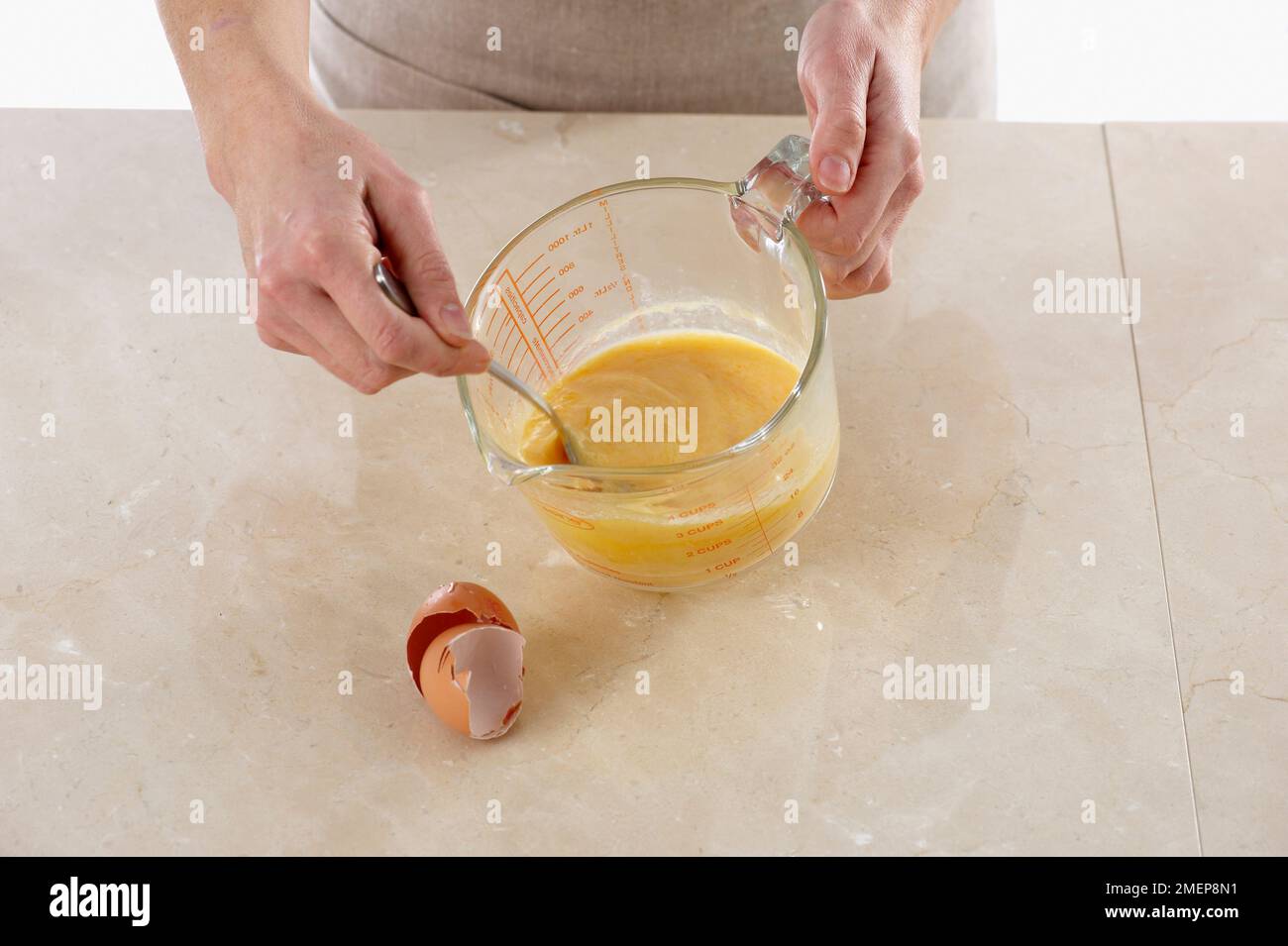 Beating egg yoke in measuring jug Stock Photo