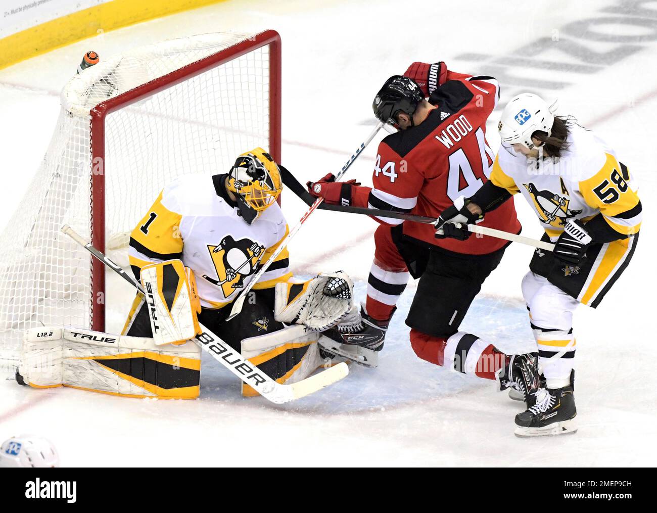 Pittsburgh Penguins goaltender Casey DeSmith (1) stops the puck as New  Jersey Devils left wing Miles Wood (44) is checked by Penguins defenseman  Kris Letang (58) during the first period of an