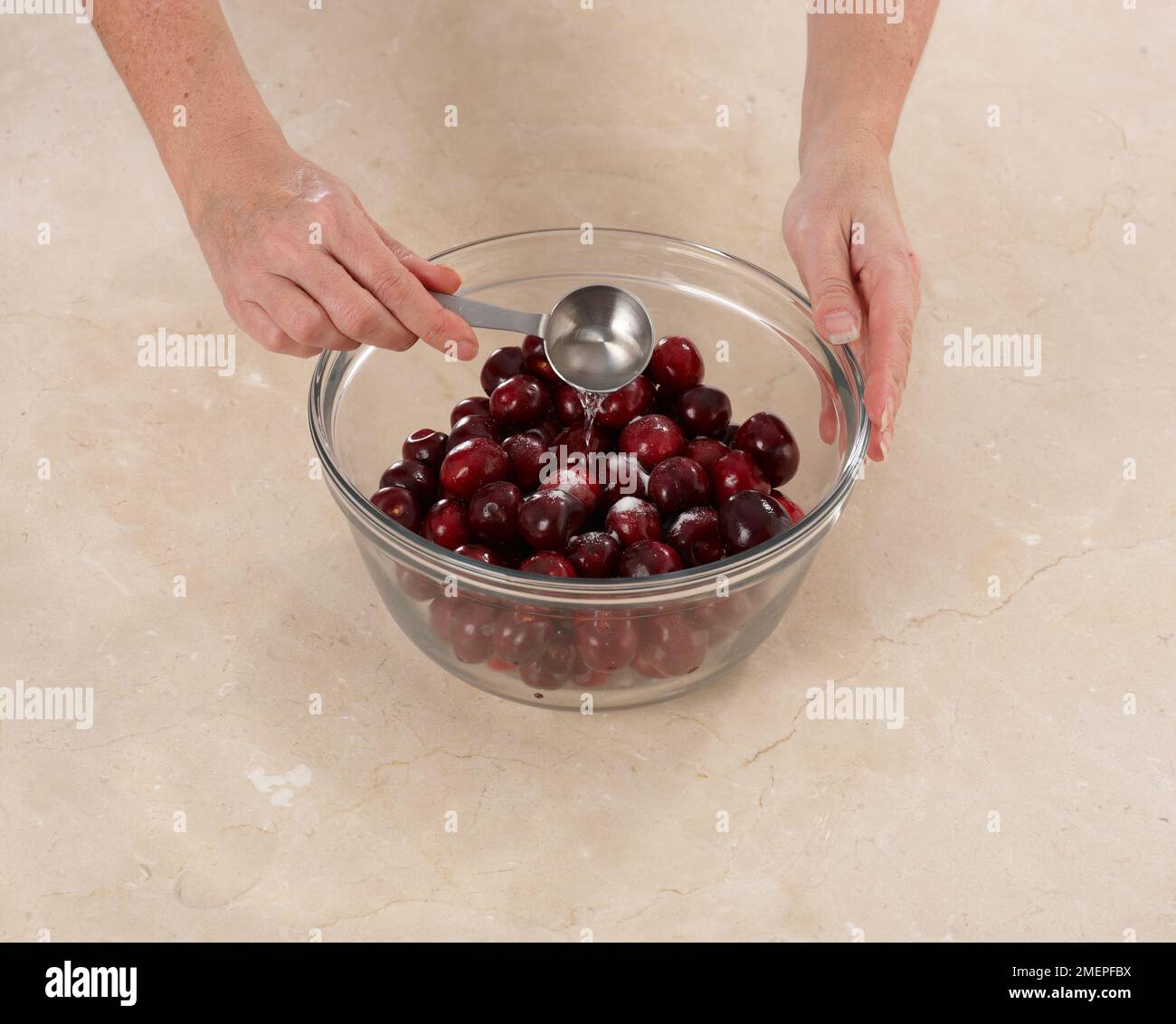 Tossing cherries with Kirsch and sugar, making Cherry Clafoutis Stock ...