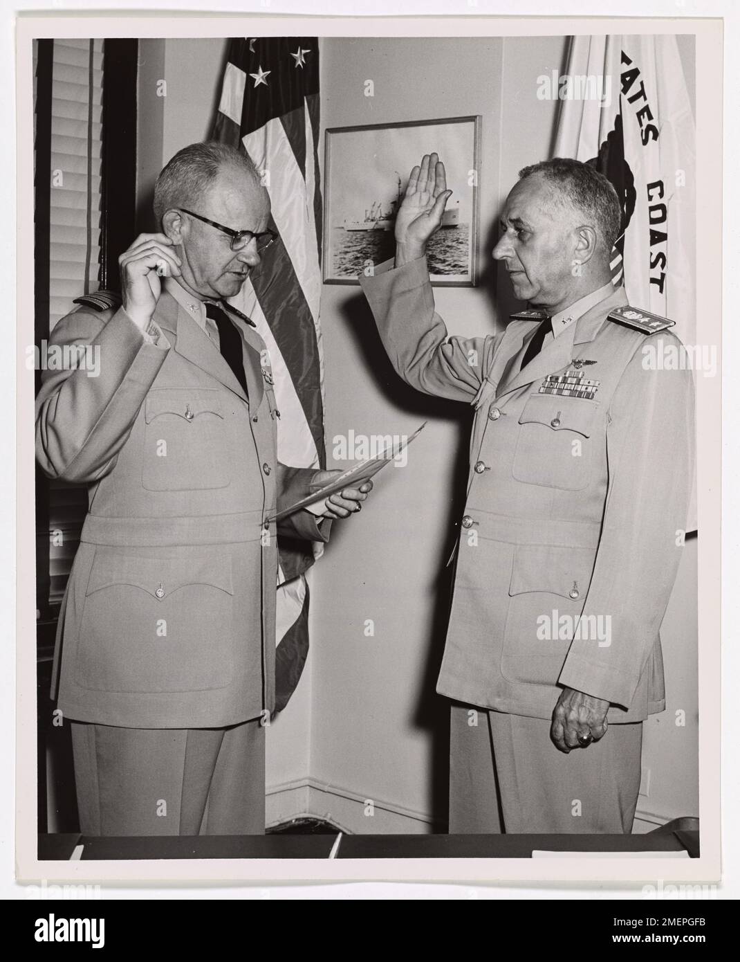 Captain Frank A. Leamy, Commander of the Ninth Coast Guard District, being sworn in as Rear Admiral. Picture shows Captain Frank A. Leamy, Commander of the Ninth Coast Guard District (Great Lakes Area) being sworn in today as Rear Admiral by Captain Harold C. Moore, Chief of Staff of the Ninth Coast Guard District. Stock Photo