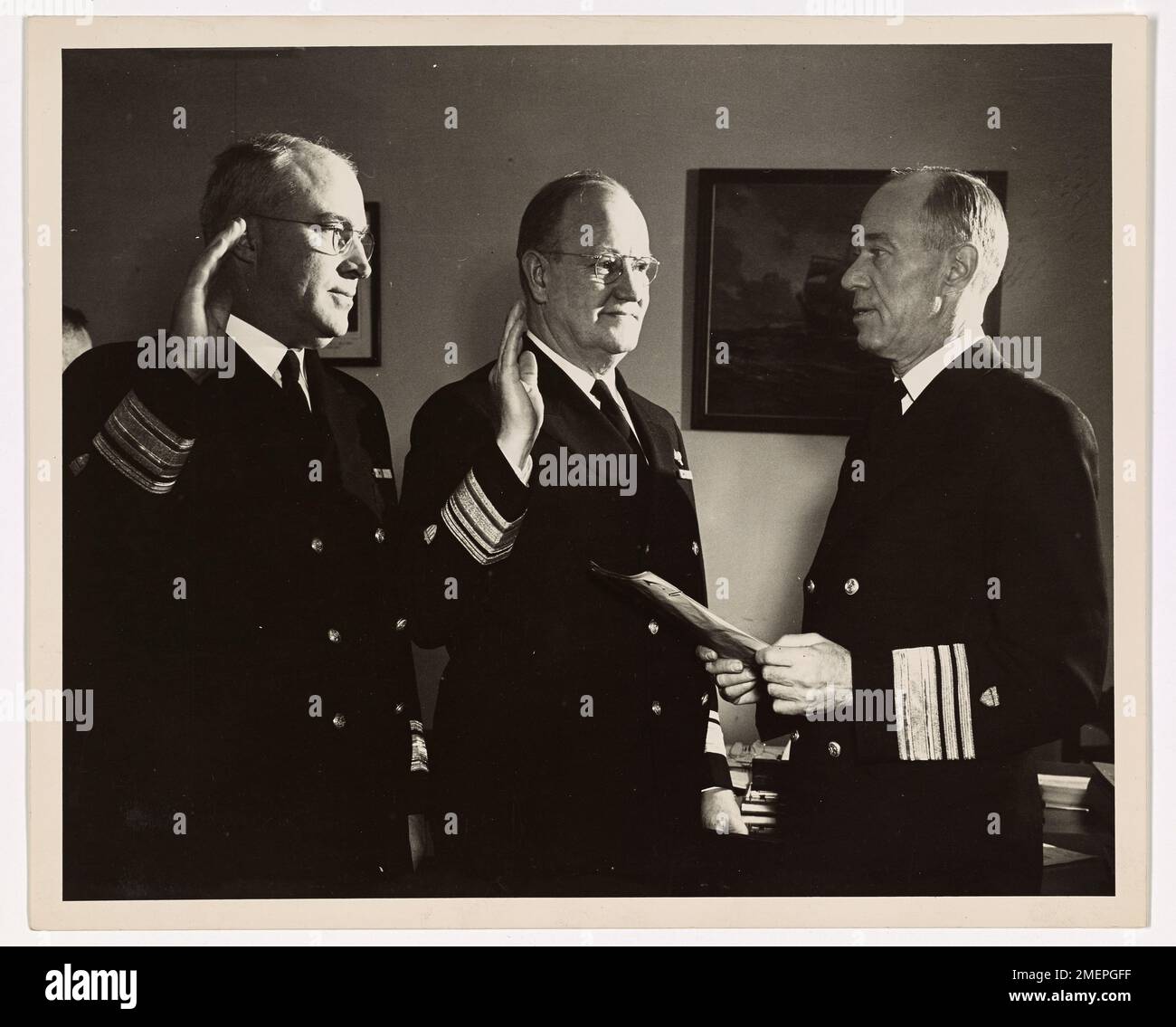 Coast Guard Officers Become Rear Admirals. Promoted to the rank of rear admiral in the U.S. Coast Guard, Commodore Joseph F. Farley, left, and Captain Philip B. Eaton, center, are sworn into their new offices by Vice Admiral Russell R. Waesche, Commandant of the Coast Guard. Both officers are on duty a Coast Guard Headquarters, Washington, D.C. Rear Admiral Farley, of Alexandria, Va., is Assistant Chief of Operations, and Rear Admiral Eaton, of Rock Creek Park, Washington, is Assistant Engineer-In-Chief. Stock Photo