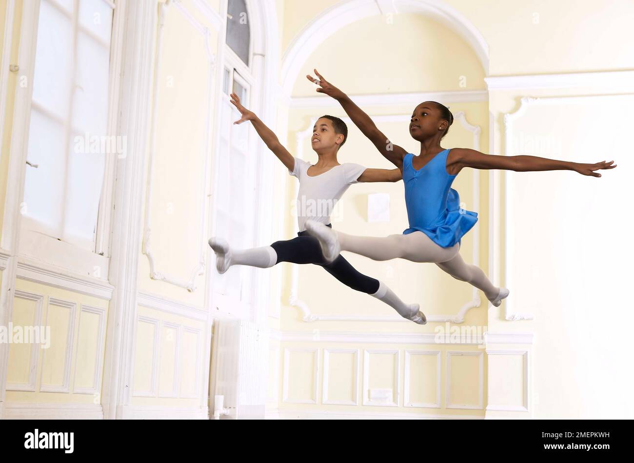 Boy and girl ballet dancers performing a grand jete jumping step Stock Photo