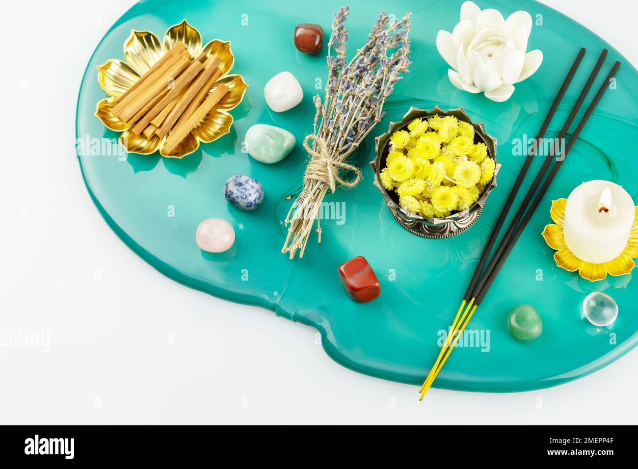 Self-care, healing composition with candle, aroma sticks, chakra stones, sandalwood sticks and dry flowers on green marble podium. Concept of relaxing Stock Photo