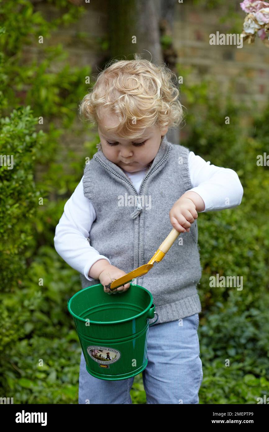 Toddler standing holding a bucket and spade, 2 years 4 months Stock
