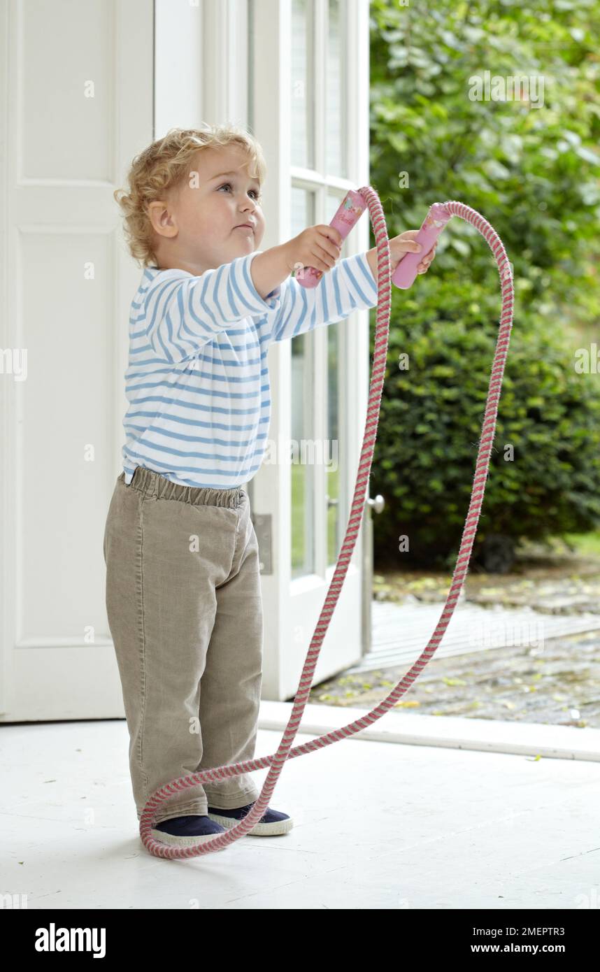 Boy holding skipping rope in doorway, 2 years 4 months Stock Photo - Alamy