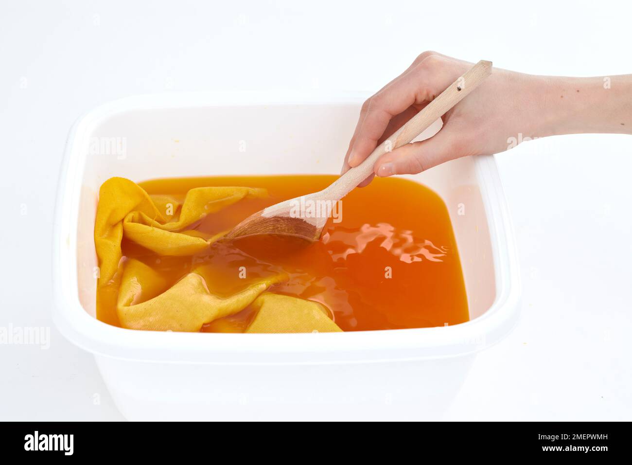 Dyeing fabric, using wooden spoon to move fabric in dye, close-up Stock Photo