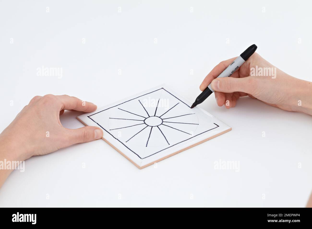 Using marker pen to draw design on white ceramic tile, closeup Stock