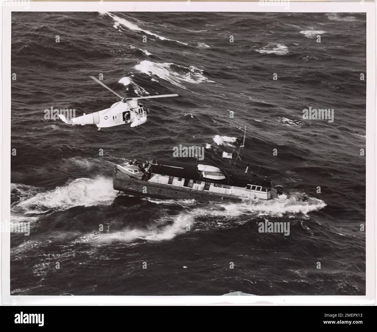 A U.S. Coast Guard HH-52A Flying Boat Helicopter is shown rescuing ...