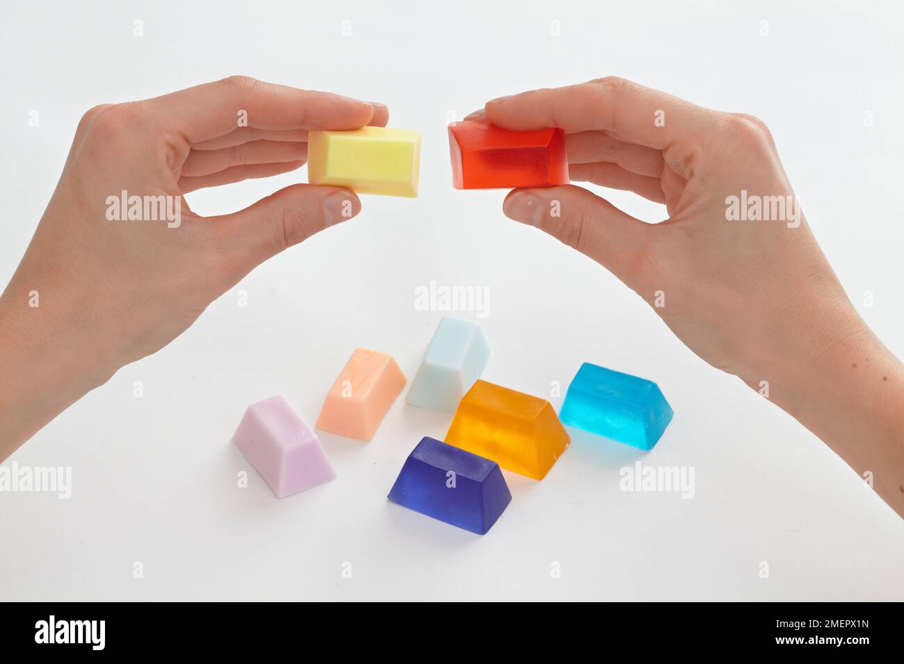 Holding small blocks of opaque and solid colour soap, close-up Stock Photo