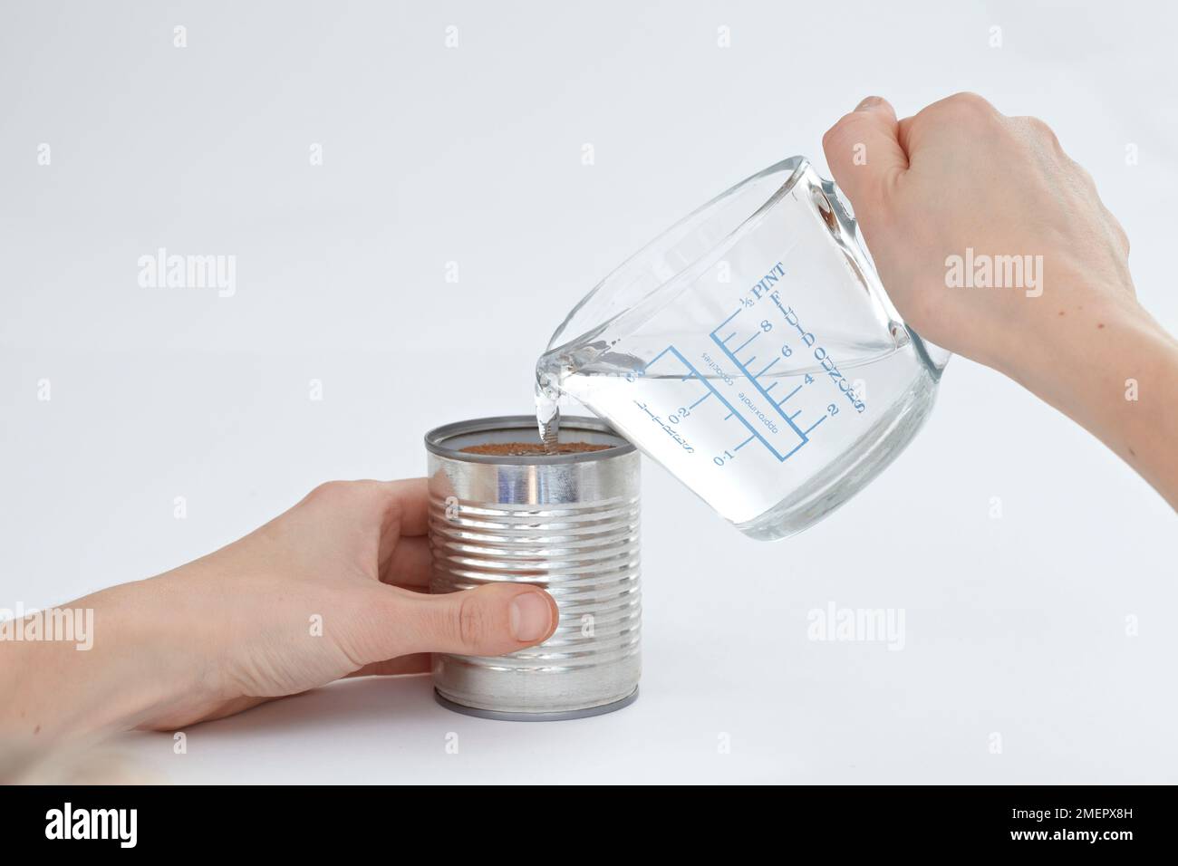 Adding water to tin can packed with sand to prevent denting, close-up, making tin can lantern Stock Photo