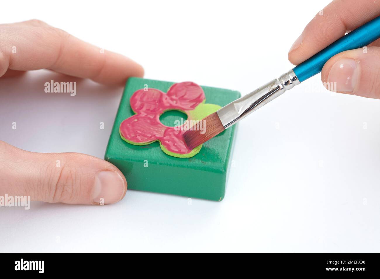 Applying fabric paint to flower shaped craft foam on printing block, close-up Stock Photo