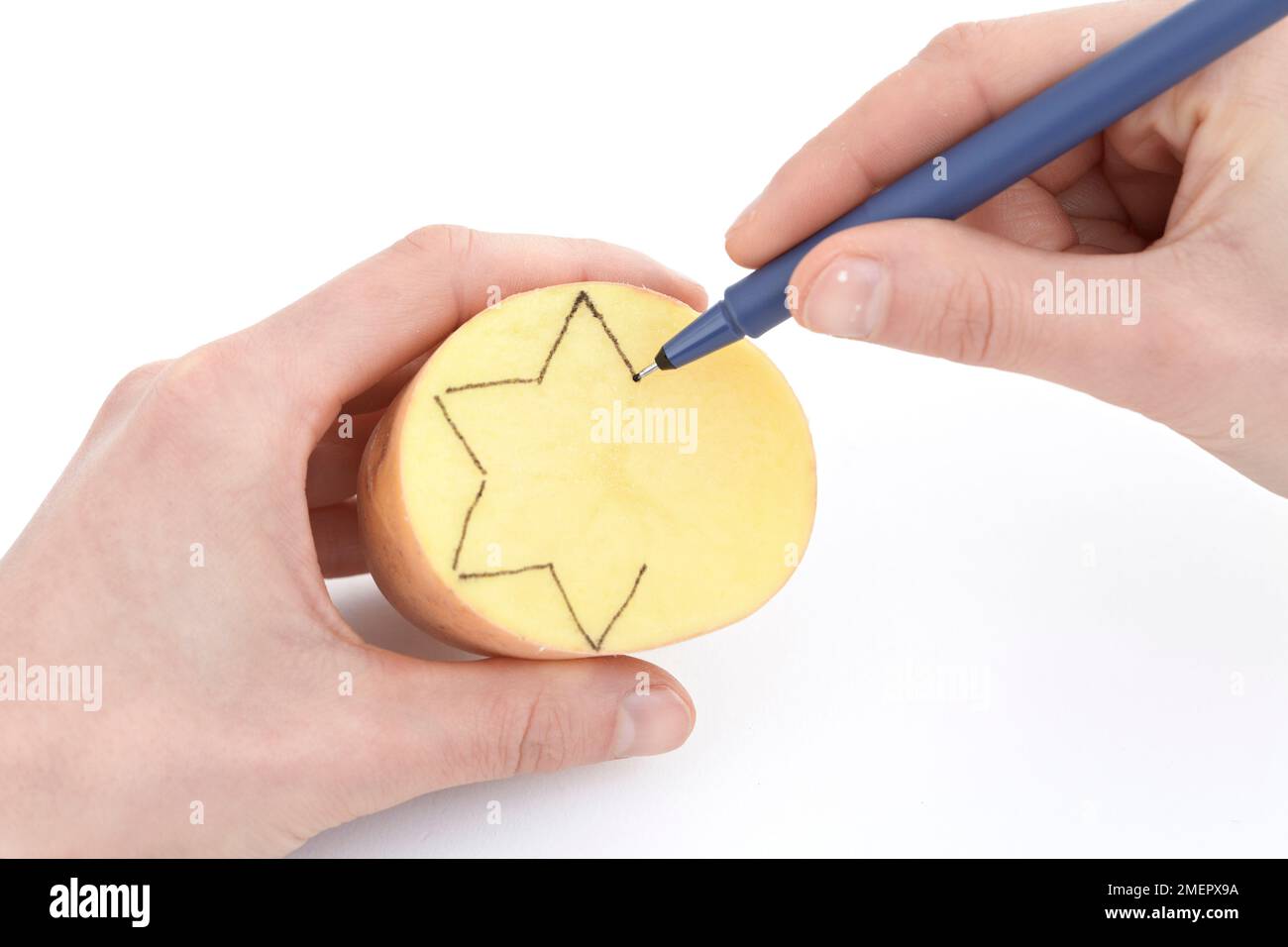 Using felt-tip-pen to draw star shape on potato stamp, close-up Stock Photo