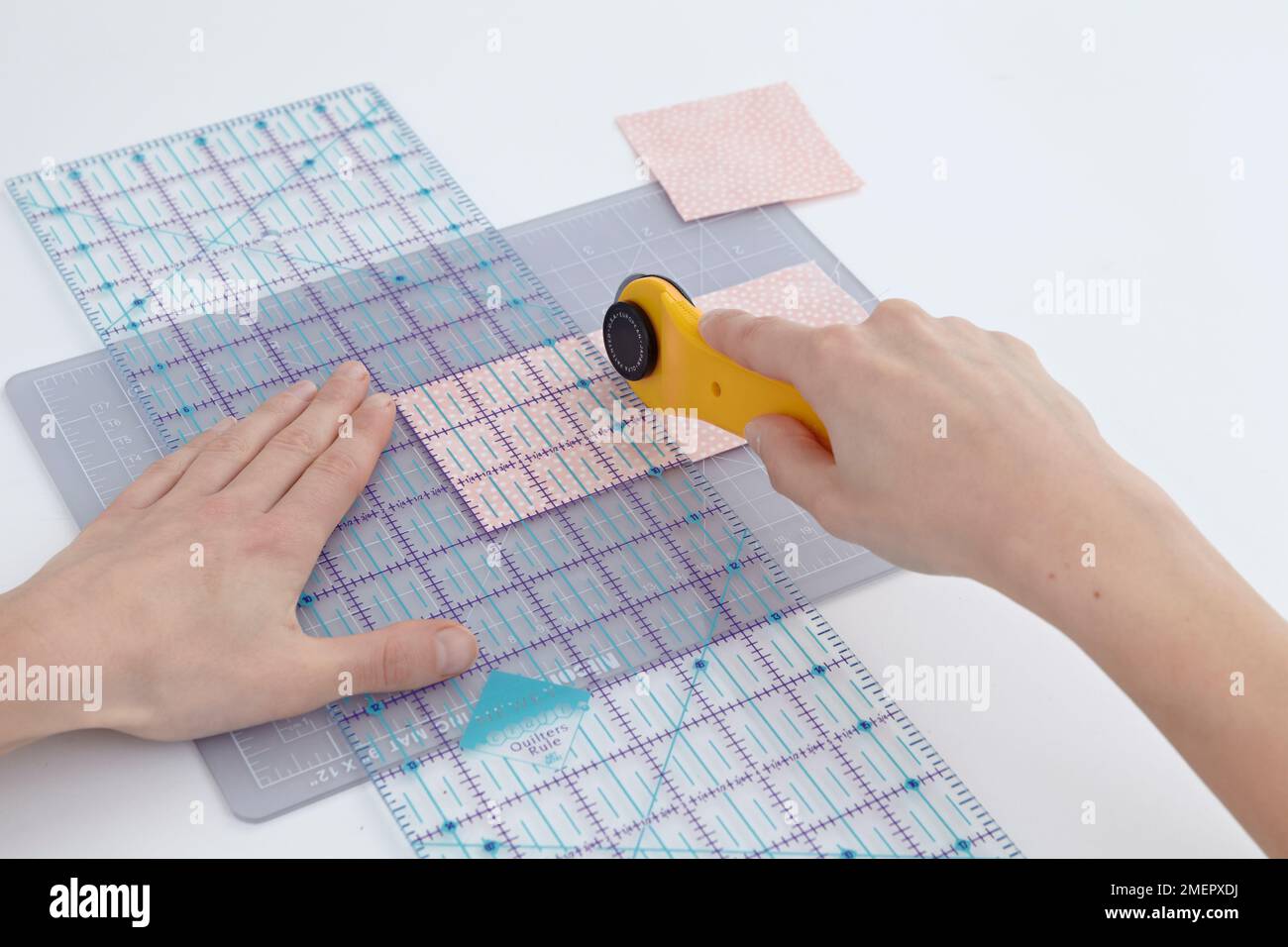 Woman cutting fabric using ruler and rotary cutter, closeup Stock