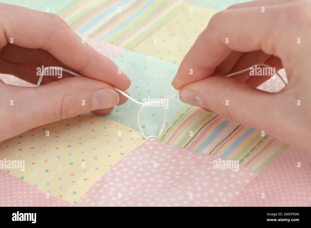 Tying reef (square) knot at each stitch to join patchwork layers, close