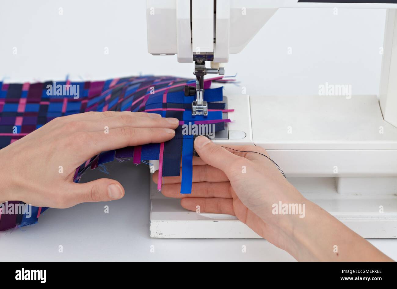 Using sewing machine to stitch around edges to secure ribbons to make