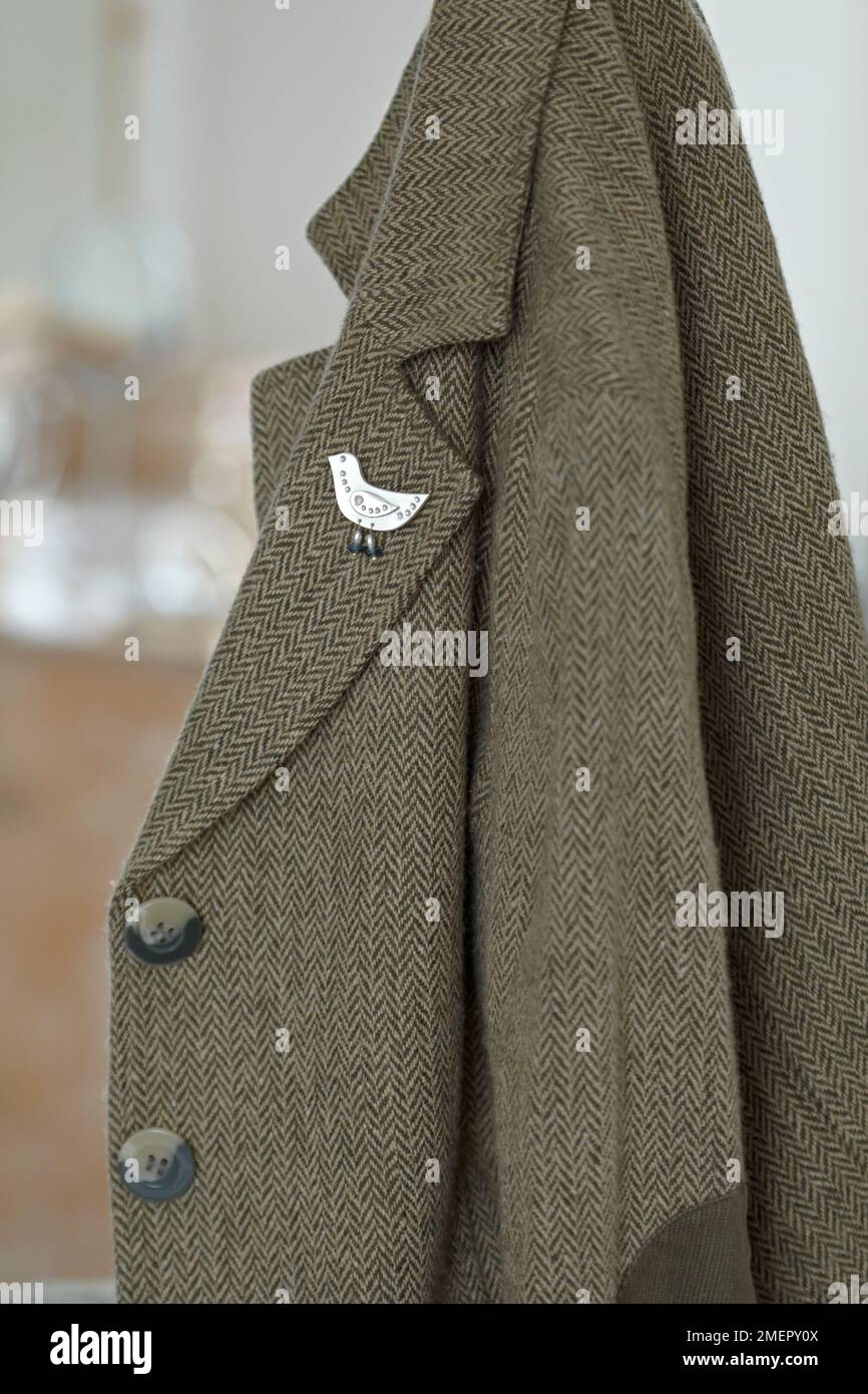 Metal clay bird brooch on lapel of women's tweed jacket, close-up Stock Photo
