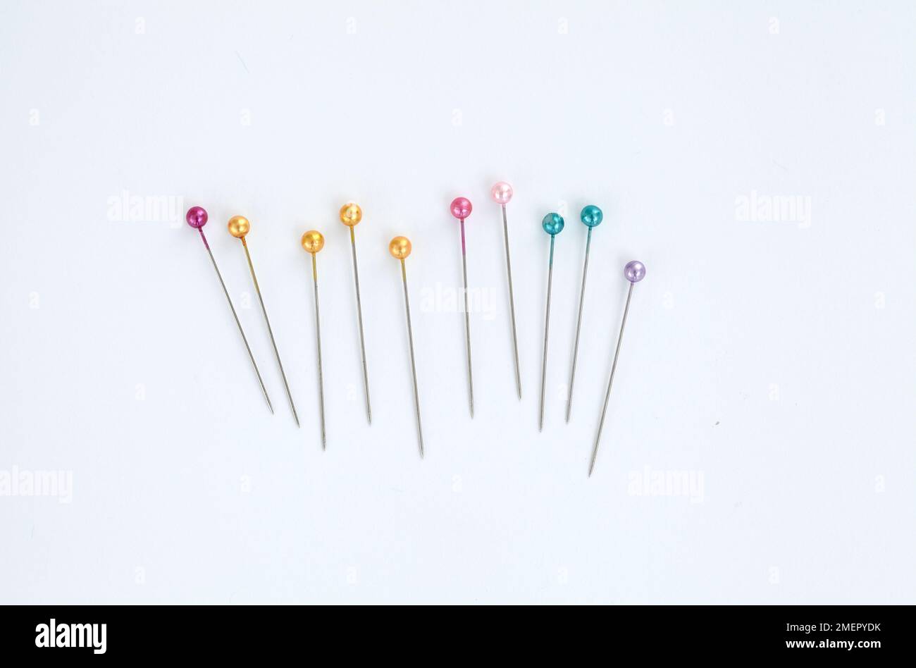 Row of sewing pins with coloured plastic heads, overhead view Stock Photo