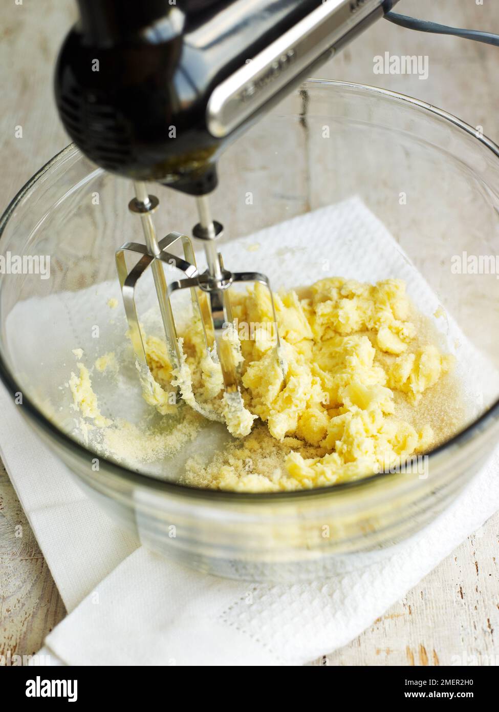 Mixing together butter and sugar in mixing bowl, using electric mixer