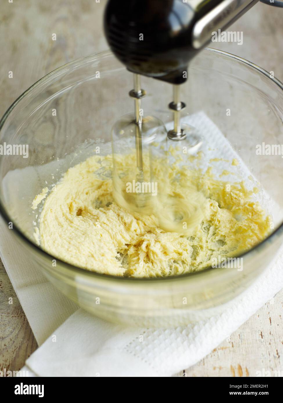 Mixing together butter and sugar in mixing bowl, using electric mixer