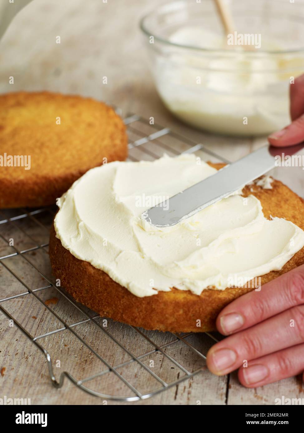 Spreading butter icing on Victoria sponge cake Stock Photo