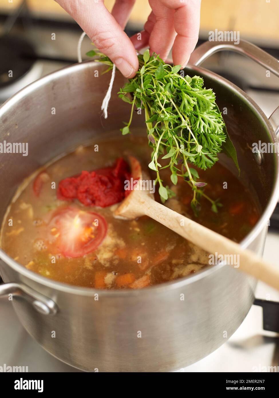 Adding bouquet garni to other ingredients in pan (cooking espagnole