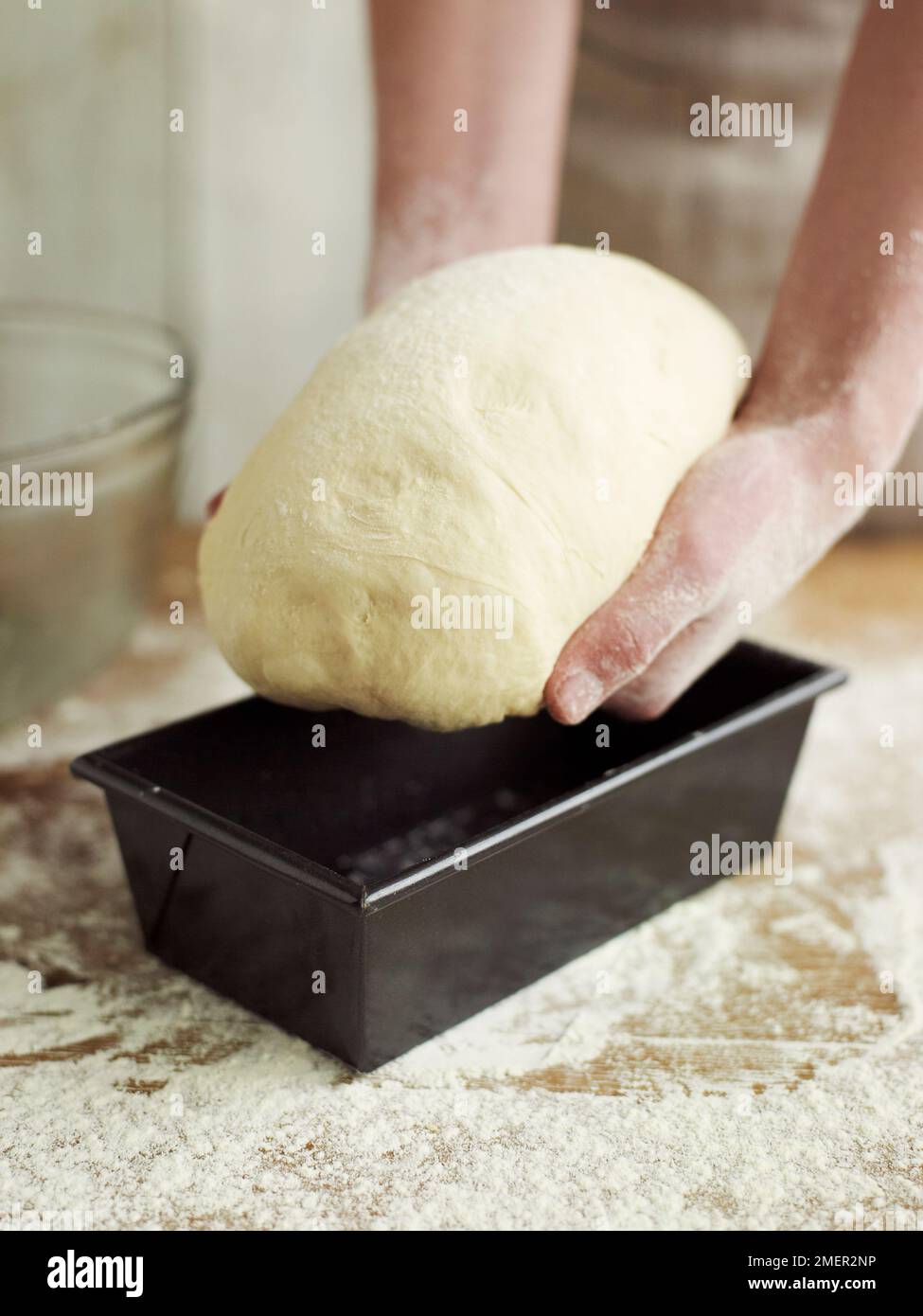 Placing kneaded and partially risen bread dough in loaf tin Stock Photo