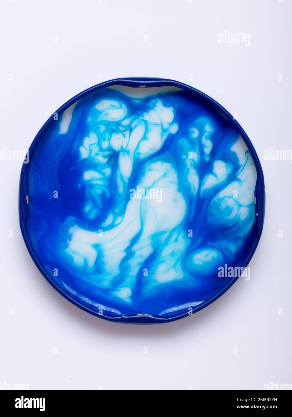 Making pattern out of mixture of milk and food colouring in lid Stock