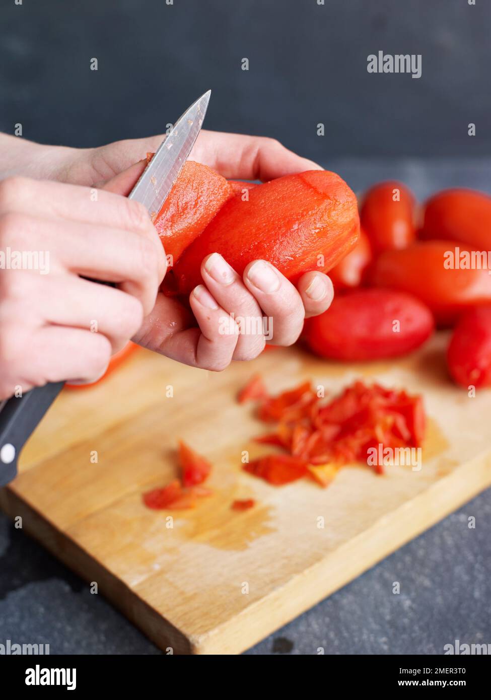 Peeling off softened skin from tomatoes (cooking tomato sauce Stock